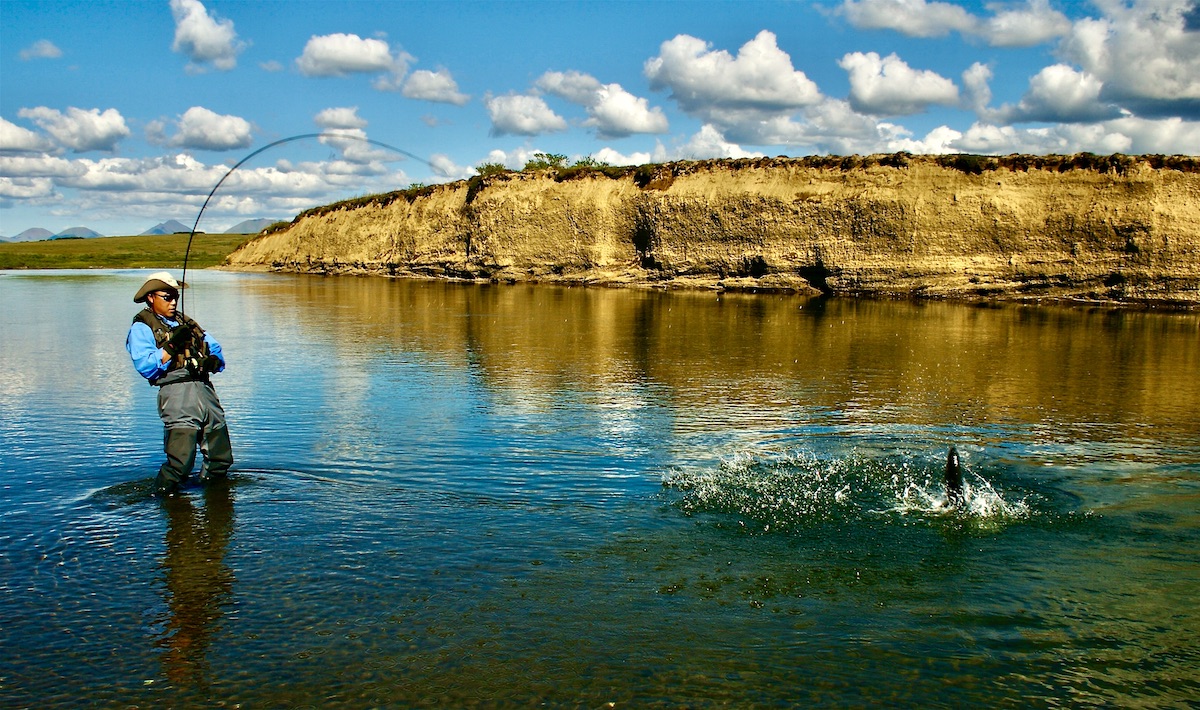 fly fisher fighting fish