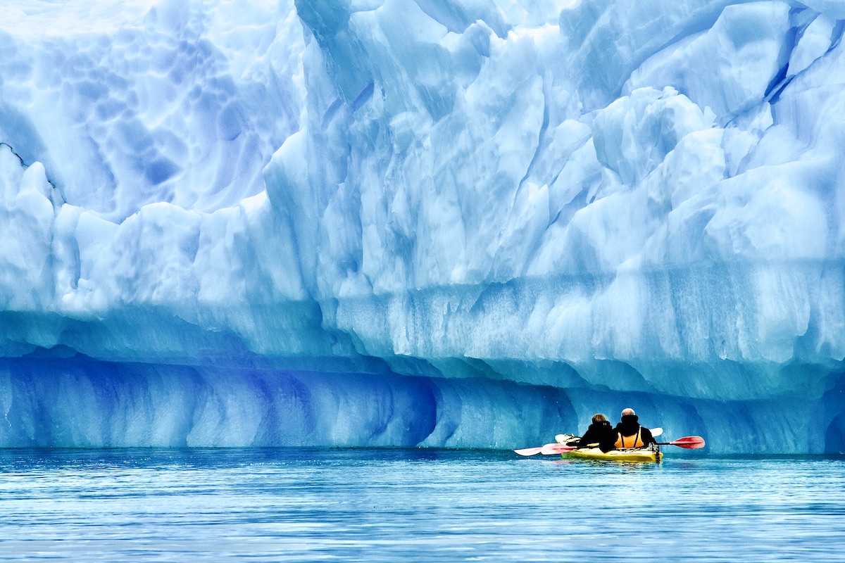 kayakers by an iceberg